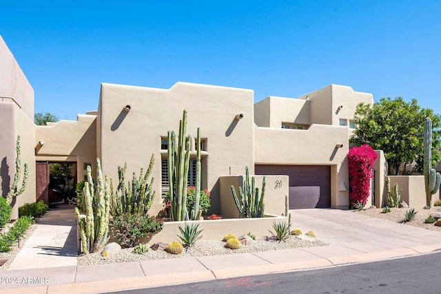 southwest-style home with driveway, fence, and stucco siding