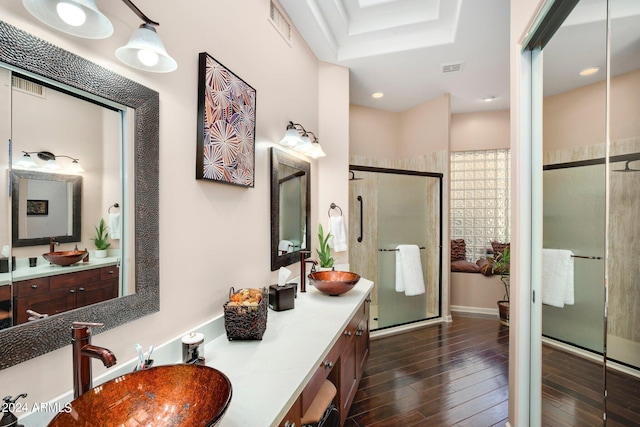 full bathroom with a stall shower, visible vents, a sink, and wood finished floors