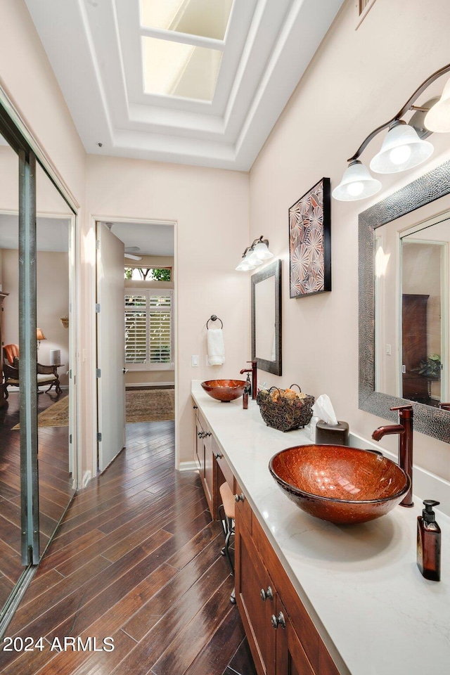 full bathroom with double vanity, a sink, baseboards, and wood finished floors