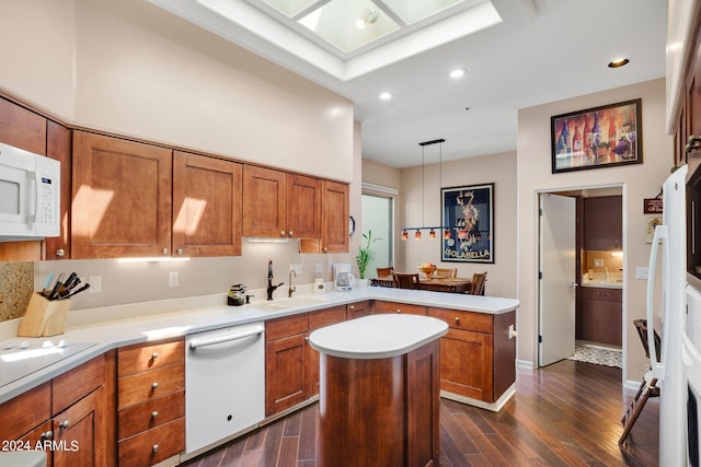 kitchen featuring pendant lighting, light countertops, brown cabinetry, a sink, and white appliances