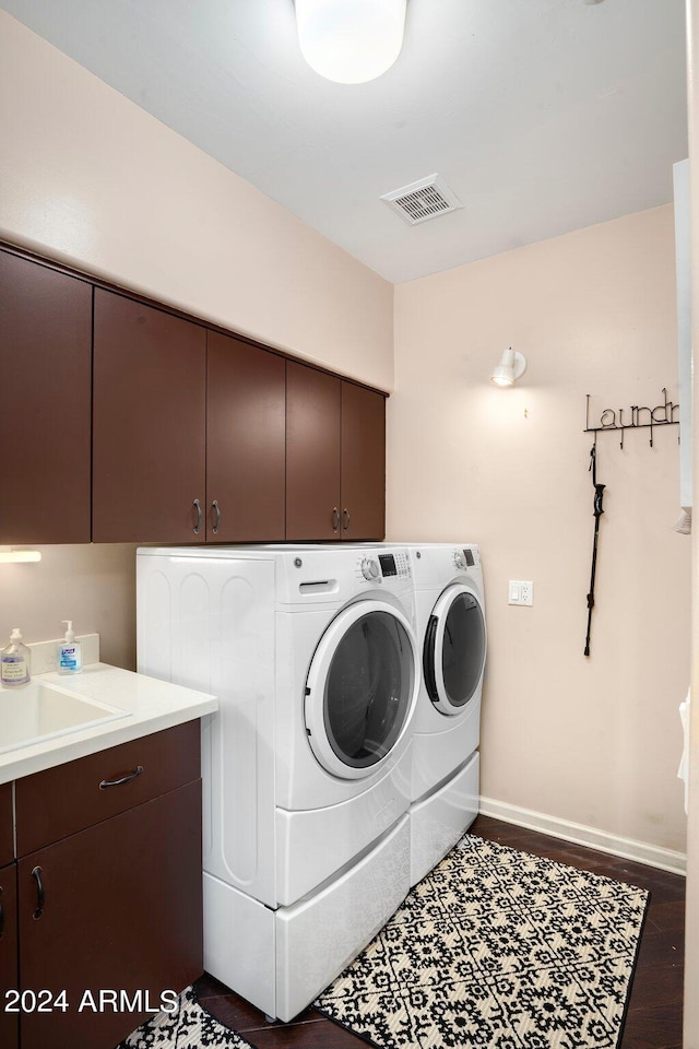 washroom featuring cabinet space, baseboards, visible vents, dark wood finished floors, and washing machine and clothes dryer