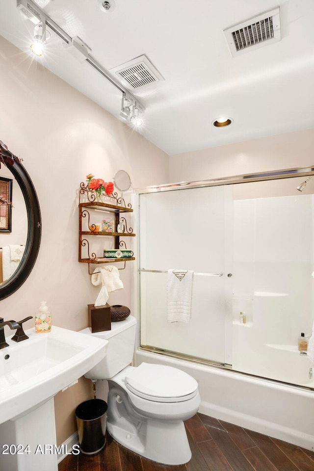 full bathroom featuring toilet, wood tiled floor, enclosed tub / shower combo, and visible vents