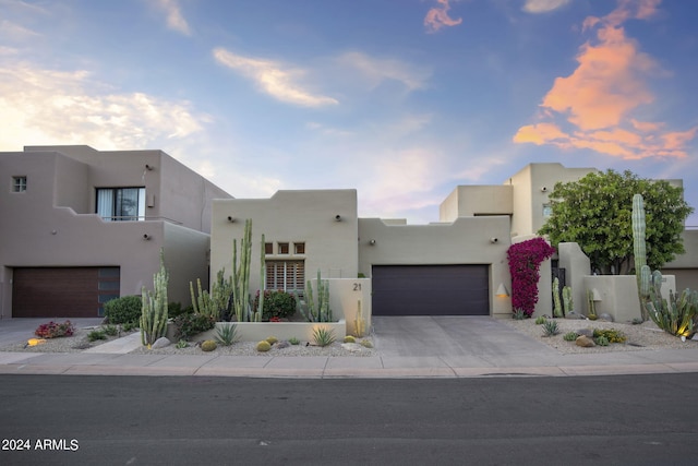 pueblo-style home with driveway, a garage, and stucco siding