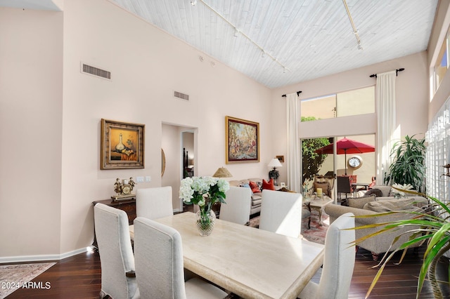 dining space featuring a towering ceiling, baseboards, visible vents, and dark wood-style flooring