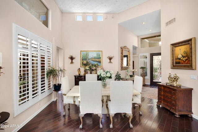 dining space featuring dark wood-style floors, a towering ceiling, visible vents, and baseboards