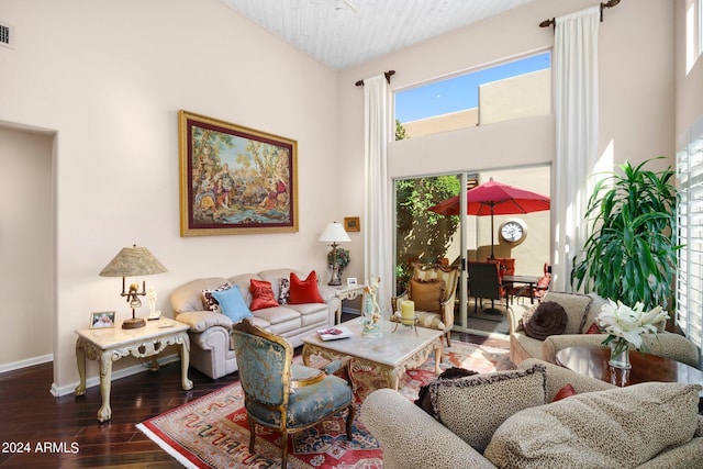 living area with baseboards, visible vents, dark wood finished floors, and a high ceiling