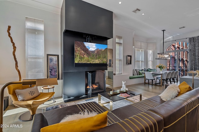 living room with wood-type flooring, an inviting chandelier, and a multi sided fireplace