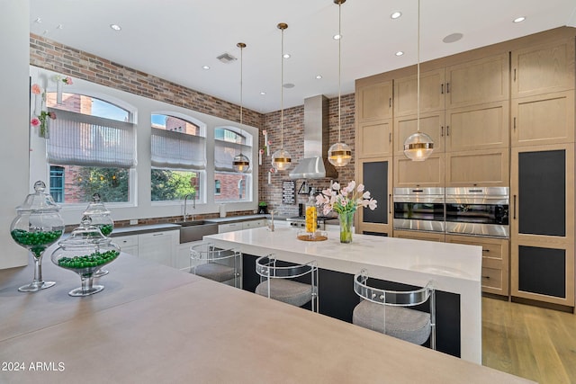 kitchen with brick wall, wall chimney range hood, and stainless steel oven