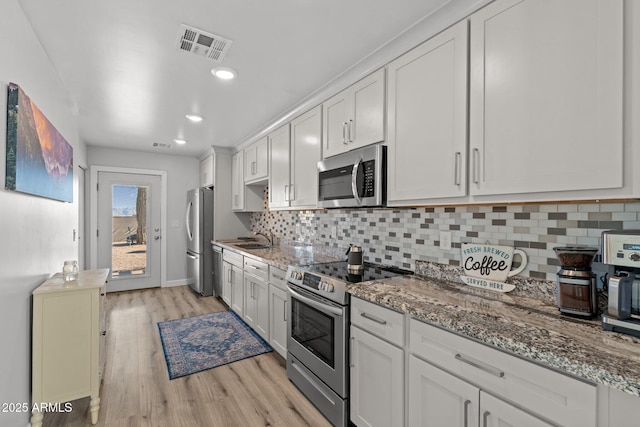 21647 W Laura St, Wittmann, AZ 85361 - kitchen featuring stainless steel appliances, light wood-style flooring, backsplash, light stone countertops, and white cabinets