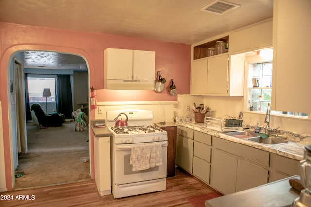 kitchen with white cabinets, sink, carpet, and white gas stove