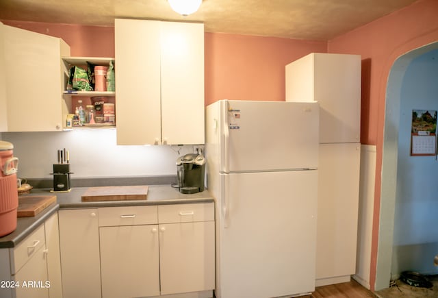 kitchen featuring white cabinets, white fridge, and wood-type flooring