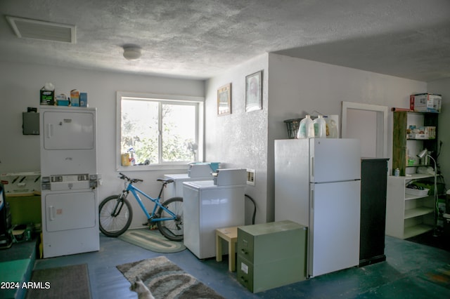 laundry area with stacked washing maching and dryer, a textured ceiling, and washer hookup