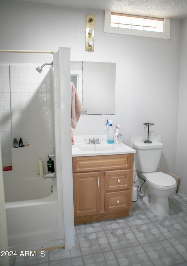 full bathroom with tiled shower / bath combo, a textured ceiling, tile floors, toilet, and vanity