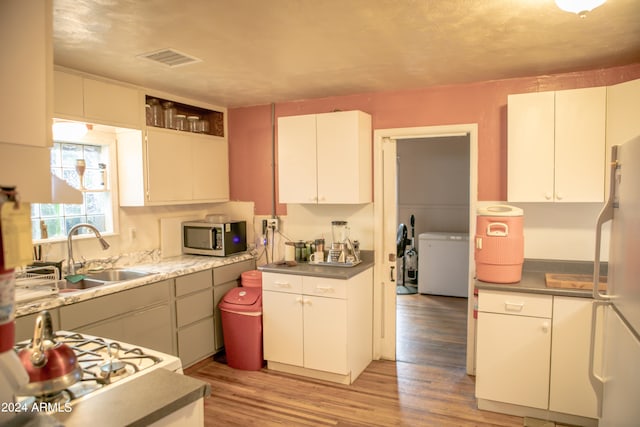 kitchen featuring light hardwood / wood-style floors, white fridge, sink, white cabinets, and washer / clothes dryer