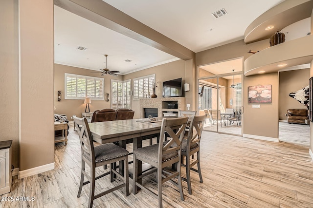 12448 N 129th Pl, Scottsdale, AZ 85259 - dining space featuring baseboards, light wood finished floors, crown molding, a fireplace, and ceiling fan