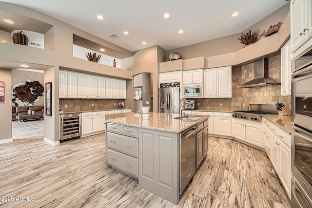 12448 N 129th Pl, Scottsdale, AZ 85259 - kitchen with beverage cooler, wall chimney range hood, appliances with stainless steel finishes, a sink, and a kitchen island with sink