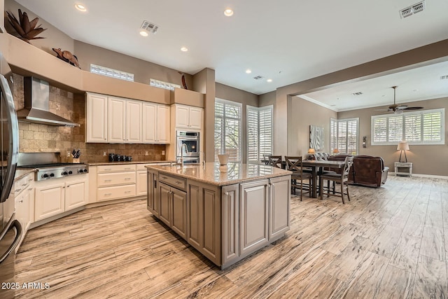 12448 N 129th Pl, Scottsdale, AZ 85259 - kitchen with wall chimney range hood, stainless steel gas stovetop, light wood-style flooring, healthy amount of natural light, and recessed lighting