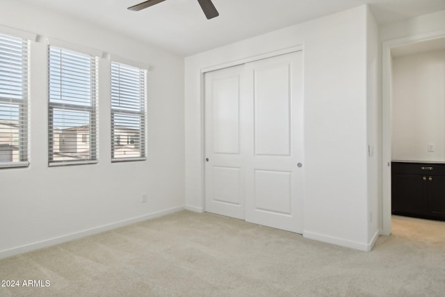 unfurnished bedroom featuring ceiling fan, light colored carpet, and a closet