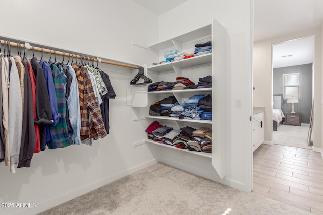 walk in closet featuring light colored carpet