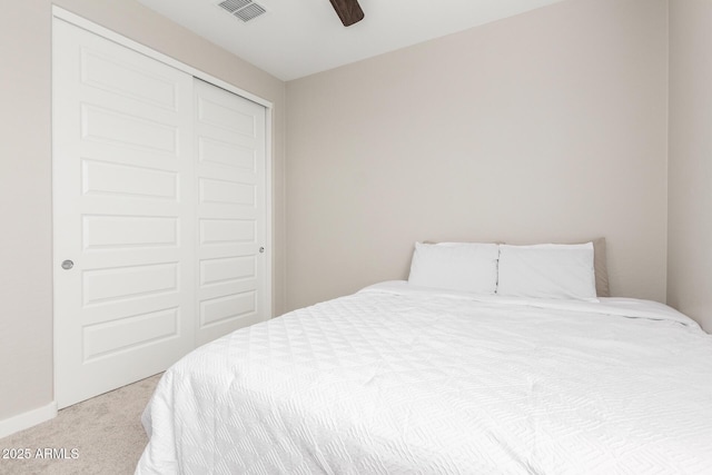 bedroom featuring light colored carpet, ceiling fan, and a closet