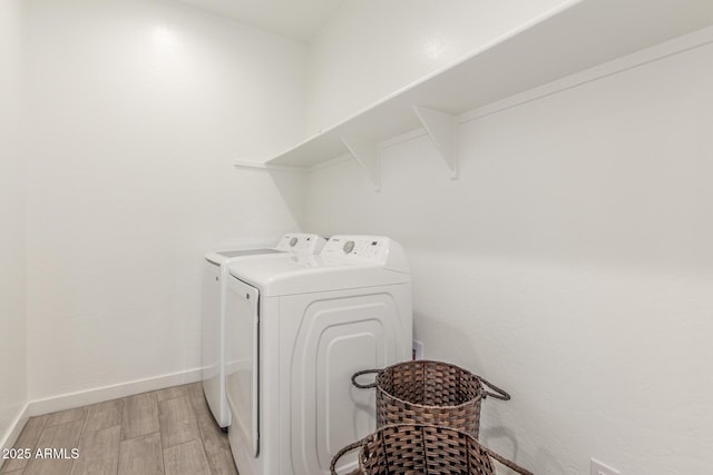 clothes washing area with independent washer and dryer and light hardwood / wood-style floors