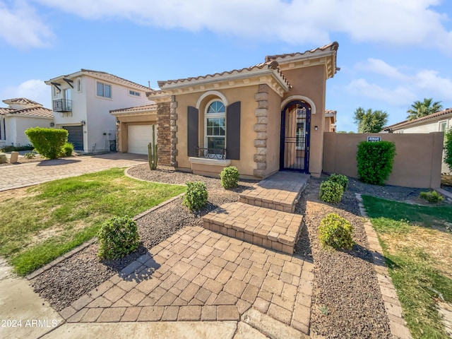 mediterranean / spanish-style home featuring a garage, a gate, fence, decorative driveway, and stucco siding