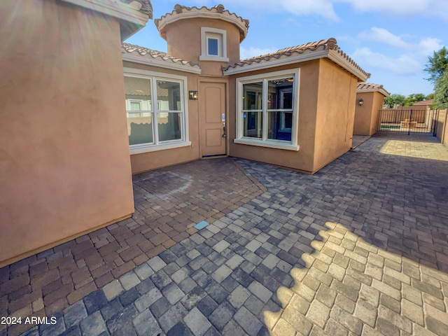 view of exterior entry featuring a gate, fence, a patio, and stucco siding