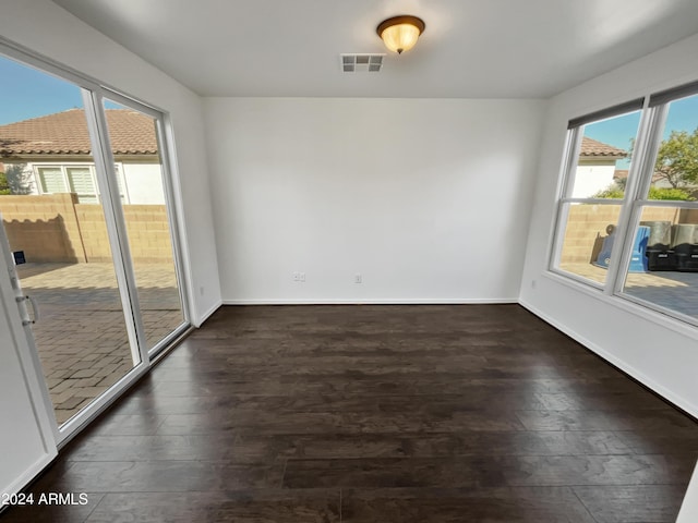 spare room with baseboards, visible vents, and dark wood-style flooring