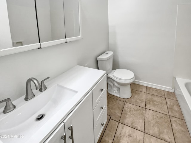 full bathroom with a washtub, toilet, vanity, baseboards, and tile patterned floors