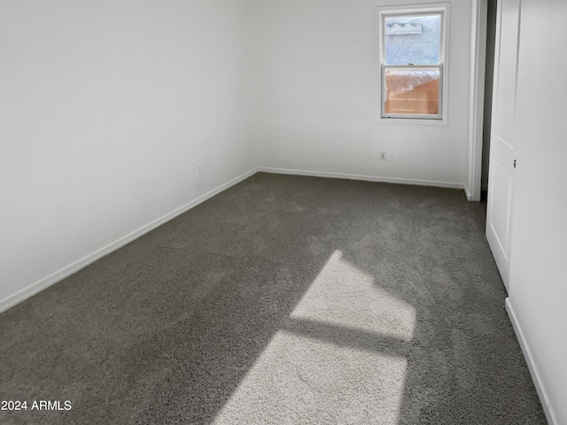 unfurnished bedroom with baseboards and dark colored carpet