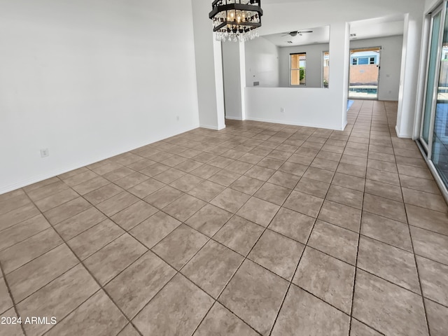 unfurnished living room featuring light tile patterned flooring and ceiling fan with notable chandelier