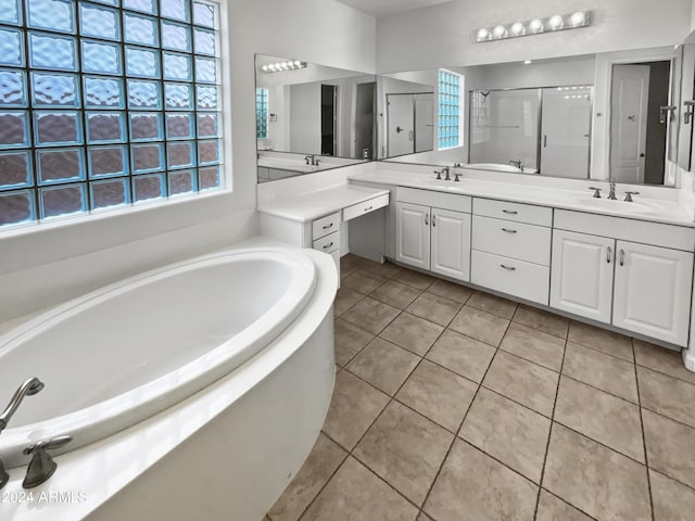 bathroom featuring double vanity, a stall shower, a sink, and tile patterned floors