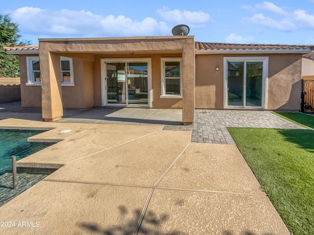 rear view of house with a patio area, an outdoor pool, and stucco siding