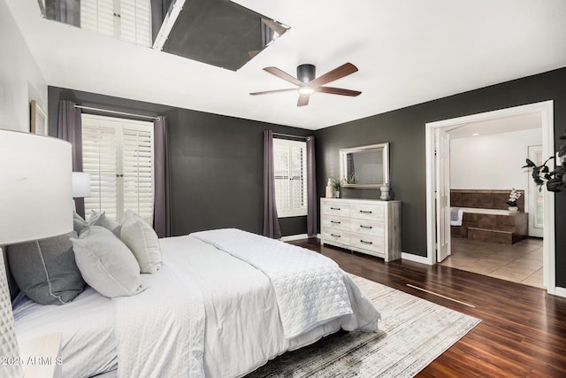 bedroom featuring ceiling fan, baseboards, ensuite bath, and wood finished floors