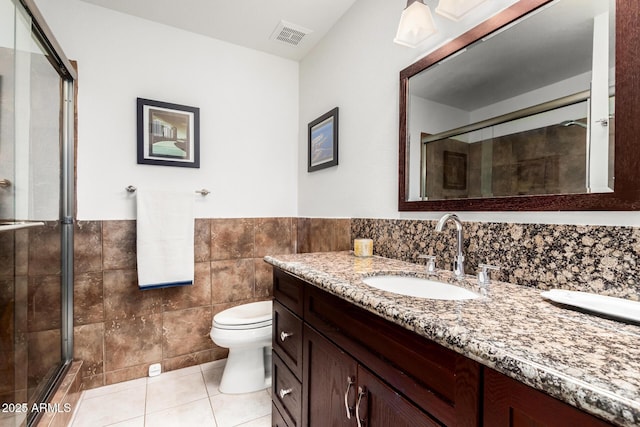 full bathroom featuring tile walls, tile patterned floors, visible vents, and a shower with door