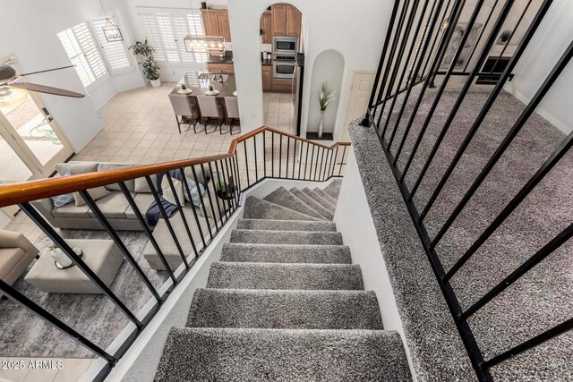 stairs featuring arched walkways and a ceiling fan