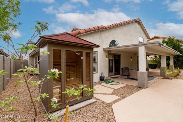 exterior space with a ceiling fan, a fenced backyard, stucco siding, a tile roof, and a patio area