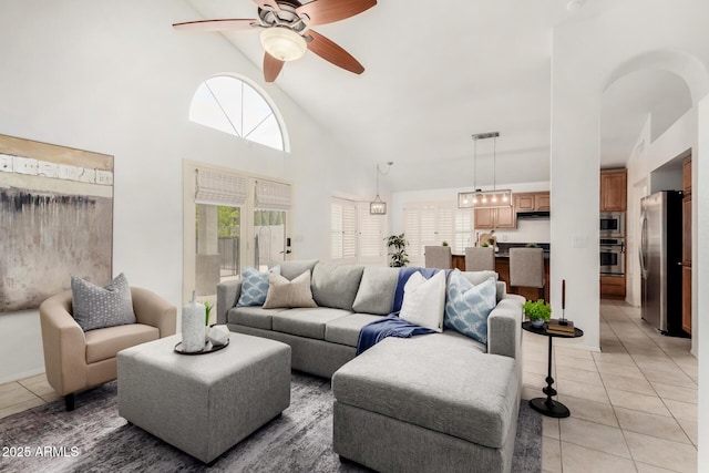 living area featuring light tile patterned floors, high vaulted ceiling, and a ceiling fan