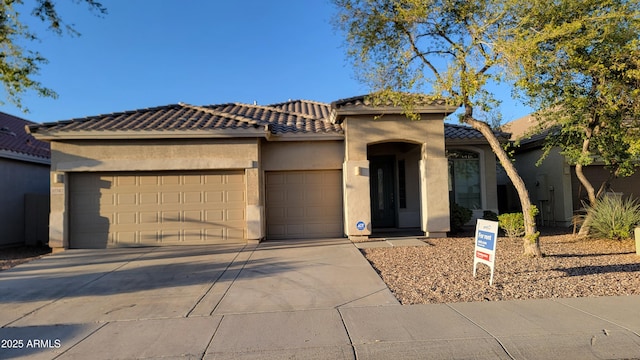 view of front of property featuring concrete driveway, a tiled roof, an attached garage, and stucco siding