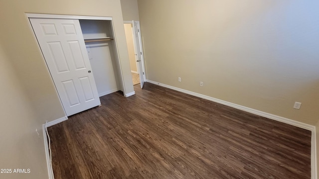 unfurnished bedroom with dark wood-style floors, baseboards, and a closet