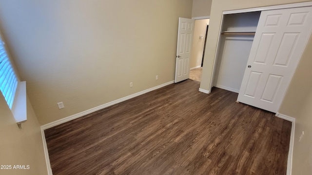 unfurnished bedroom with a closet, dark wood finished floors, and baseboards