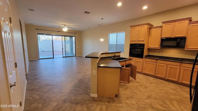 kitchen featuring visible vents, dark countertops, an island with sink, black appliances, and a sink