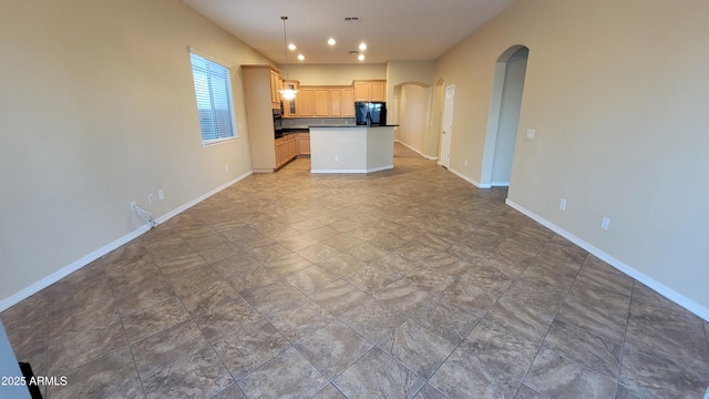 kitchen with baseboards, arched walkways, dark countertops, open floor plan, and refrigerator