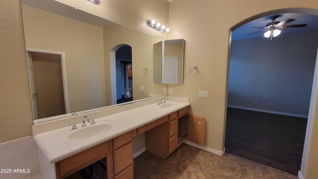 bathroom with double vanity, ceiling fan, baseboards, and a sink