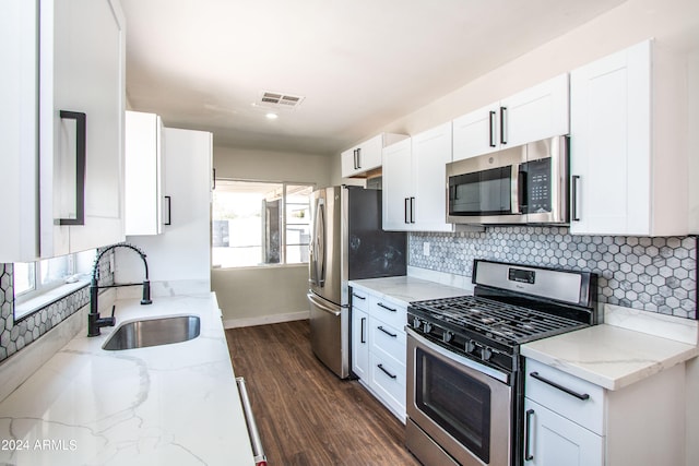 kitchen featuring appliances with stainless steel finishes, white cabinetry, light stone countertops, dark hardwood / wood-style flooring, and sink