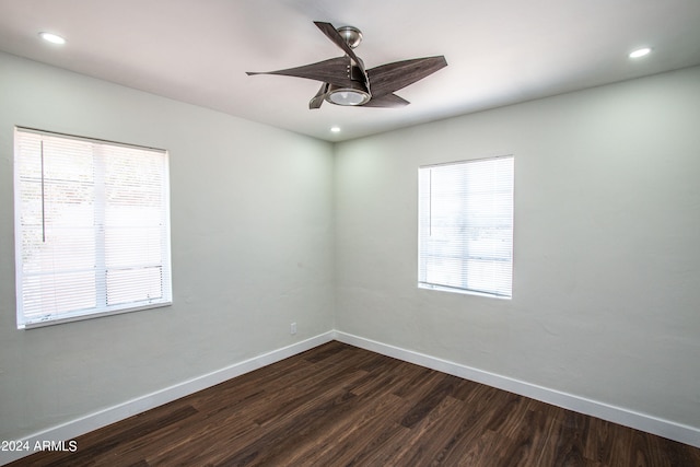 spare room featuring ceiling fan, dark wood-type flooring, and plenty of natural light