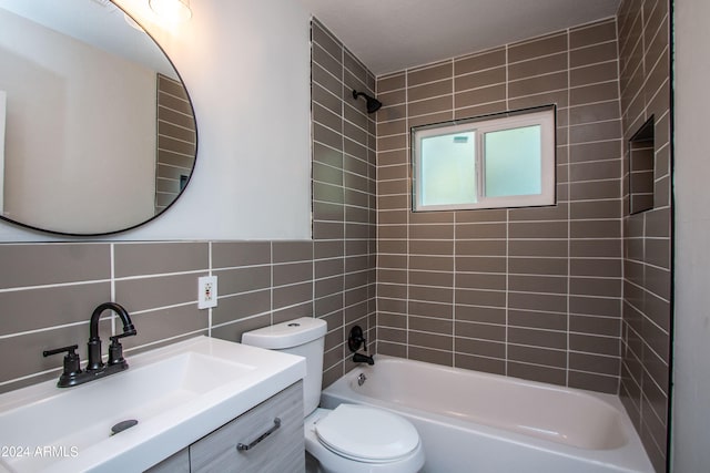 full bathroom with tile walls, decorative backsplash, tiled shower / bath combo, vanity, and toilet