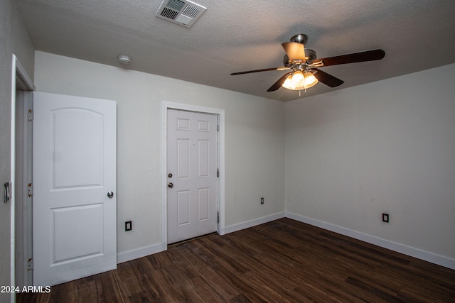 empty room with a textured ceiling, dark hardwood / wood-style flooring, and ceiling fan