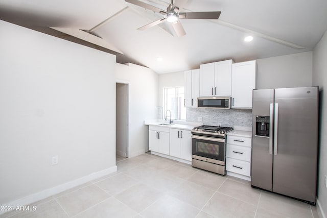 kitchen featuring appliances with stainless steel finishes, vaulted ceiling, sink, and white cabinets