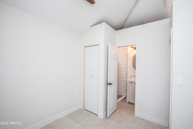 unfurnished bedroom with vaulted ceiling and light tile patterned floors